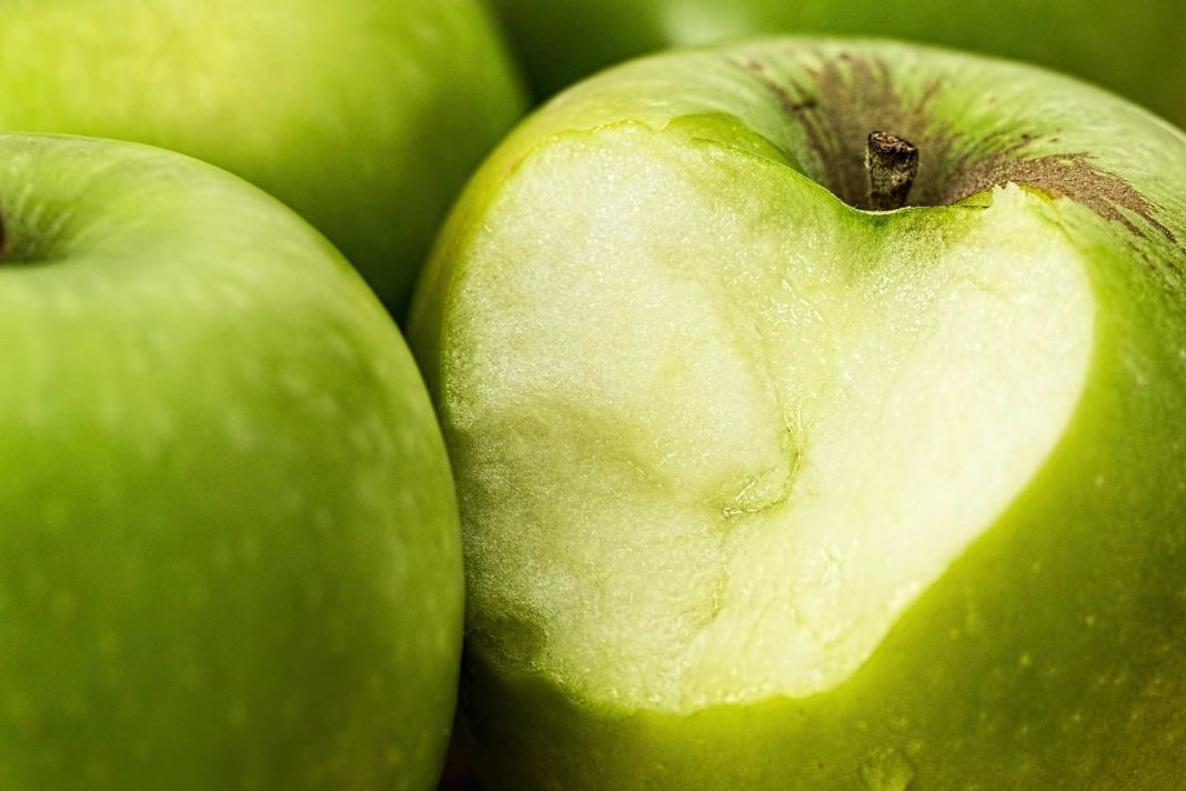Ein angebissener grüner Apfel.