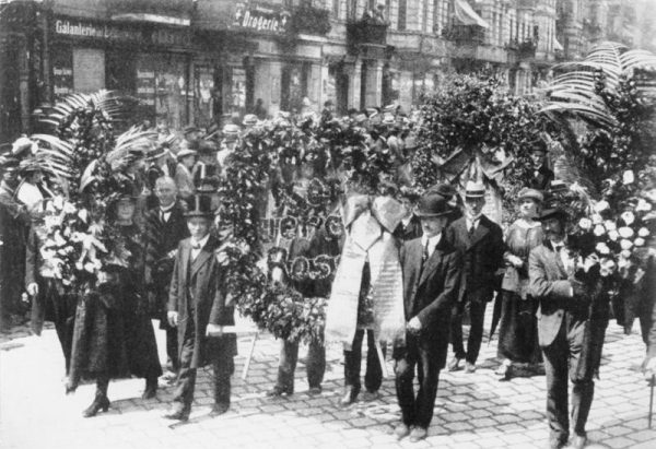 Die Beisetzung von Rosa Luxemburg am 13. Juni 1919. Riesige Kranzspenden am Anfang des Trauerzuges. Bundesarchiv, Bild 146-1976-067-25A, CC-BY-SA 3.0